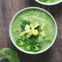 Pineapple gazpacho in a bowl topped with chopped fresh pineapple, cucumber, jalapeno, and cilantro