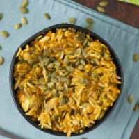 bowl of baked orzo garnished with pumpkin seeds