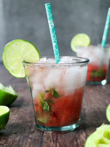 glass of watermelon smash with a blue straw and a wheel of lime for garnish
