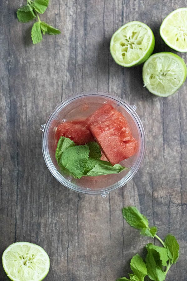 watermelon cubes and mint in a cup with juiced limes and mint leaves on the table