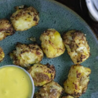 overhead photo of cauliflower tots on a blue plate with dipping sauce