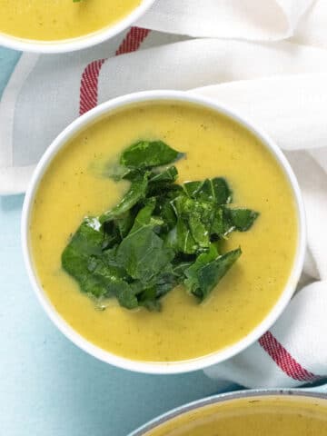 A bowl of butternut squash soup with collard greens topping