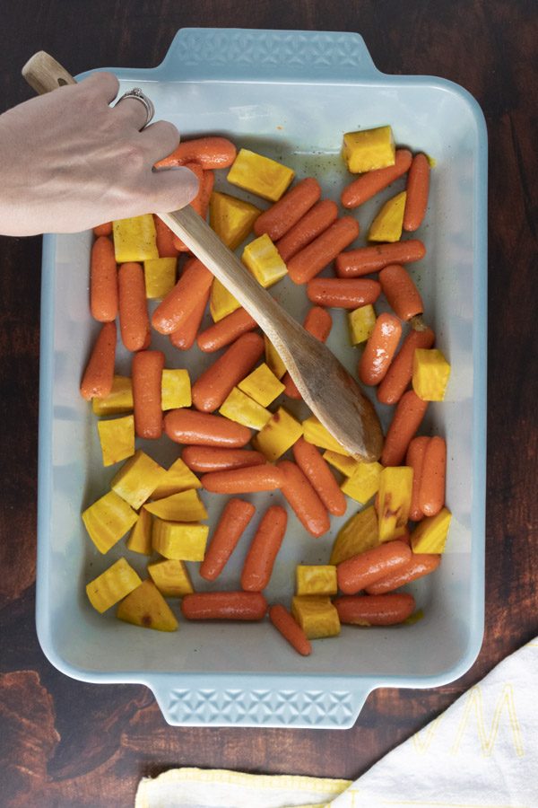stirring kid-friendly vegetables together in a roasting pan