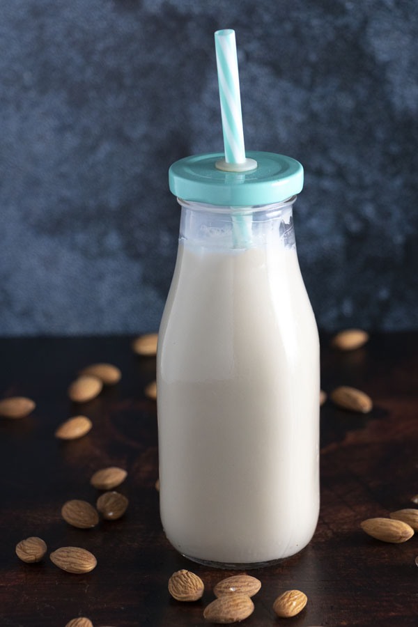 a bottle of homemade almond milk alternative on a table with almonds