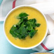 bowl of creamy, dairy-free butternut squash soup topped with greens