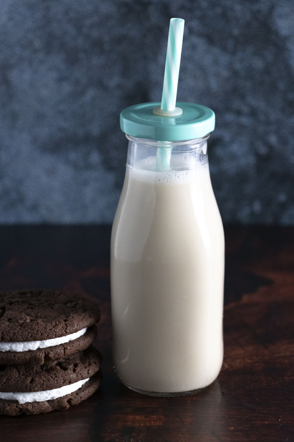 a bottle of soy milk next to stacked sandwich cookies