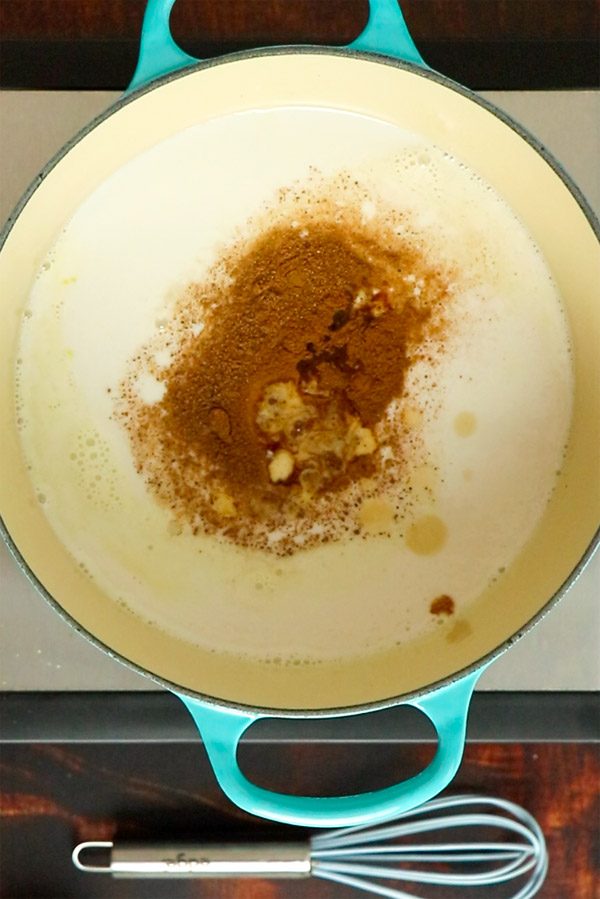 a mix of vegan milks in a pan with spices on top, waiting to be whisked together