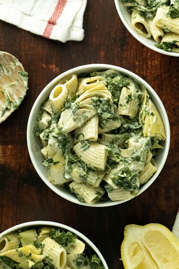 spinach artichoke pasta in a bowl on a wooden table