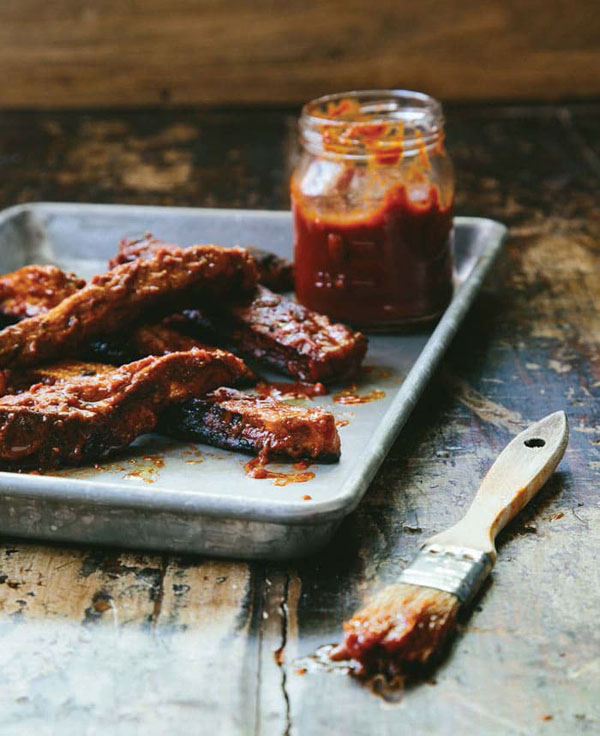 vegan ribs on a serving tray next to a jar of BBQ sauce and a sauce brush