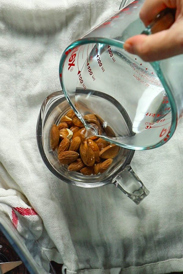 pouring hot water onto raw almonds to soak