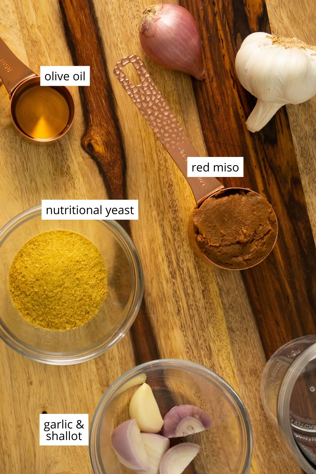 cups of miso, nutritional yeast, garlic, and shallots with text labels on each ingredient