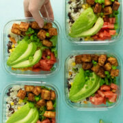 meal prep containers filled with tofu, beans and rice, and vegetables