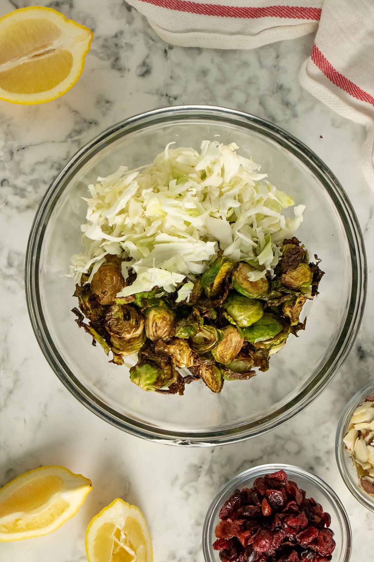 cabbage and cooked Brussels sprouts in a mixing bowl surrounded by other salad ingredients