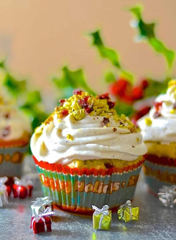 close-up of a cupcake with white fristing topped with dried cranberries and crushed pistachios