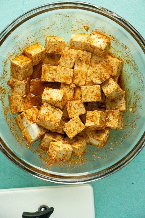 cubed tofu marinating in a glass bowl