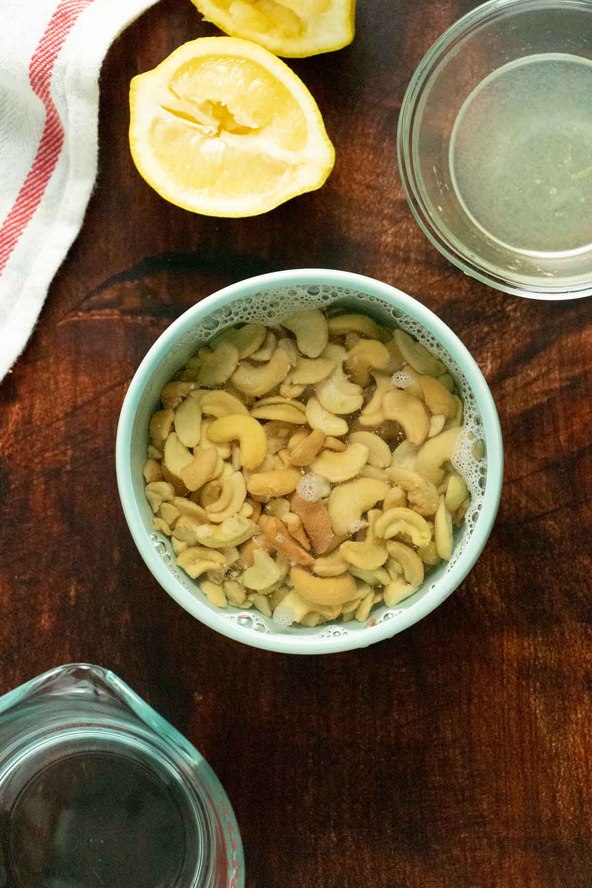 photo of cashews soaking a bowl with lemons, lemon juice, and water on bowls on the table