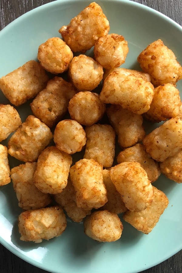 close-up of crispy tater tots on a blue plate