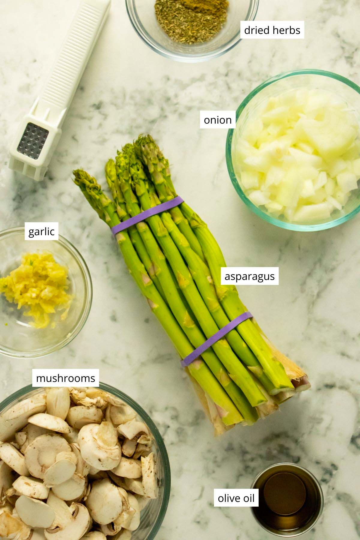 asparagus, mushrooms, and other ingredients in containers on a marble table
