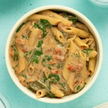 overhead photo of instant pot pasta in creamy sauce with tomatoes and spinach