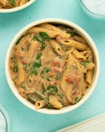 overhead photo of instant pot pasta in creamy sauce with tomatoes and spinach
