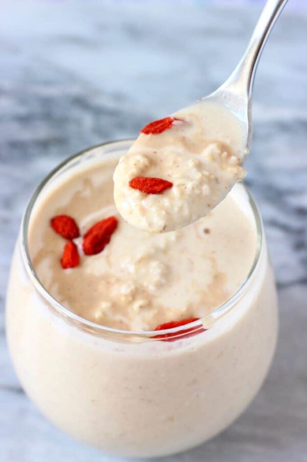 spoon holding up a bite of peanut butter oatmeal with goji berries sprinkled on top