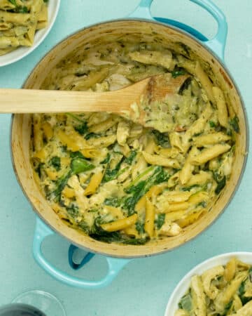A Dutch oven with Pasta and spinach in a creamy sauce