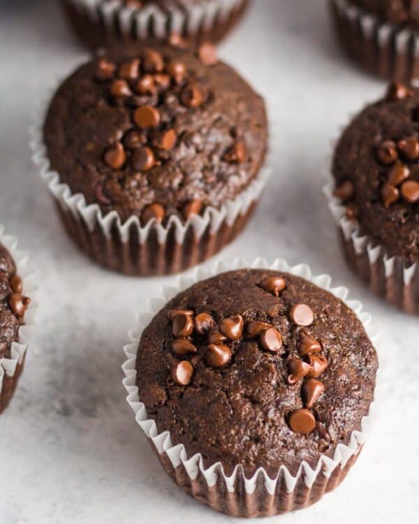 close-up of vegan double chocolate muffins in white pan liners on a white table