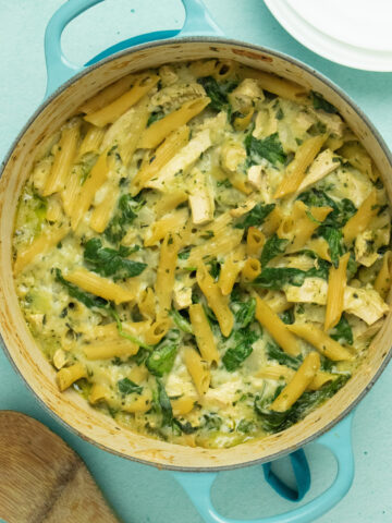 A Dutch oven with Pasta, spinach, and vegan chicken in a creamy sauce