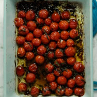 overhead photo of roasted cherry tomatoes in a light blue baking pan