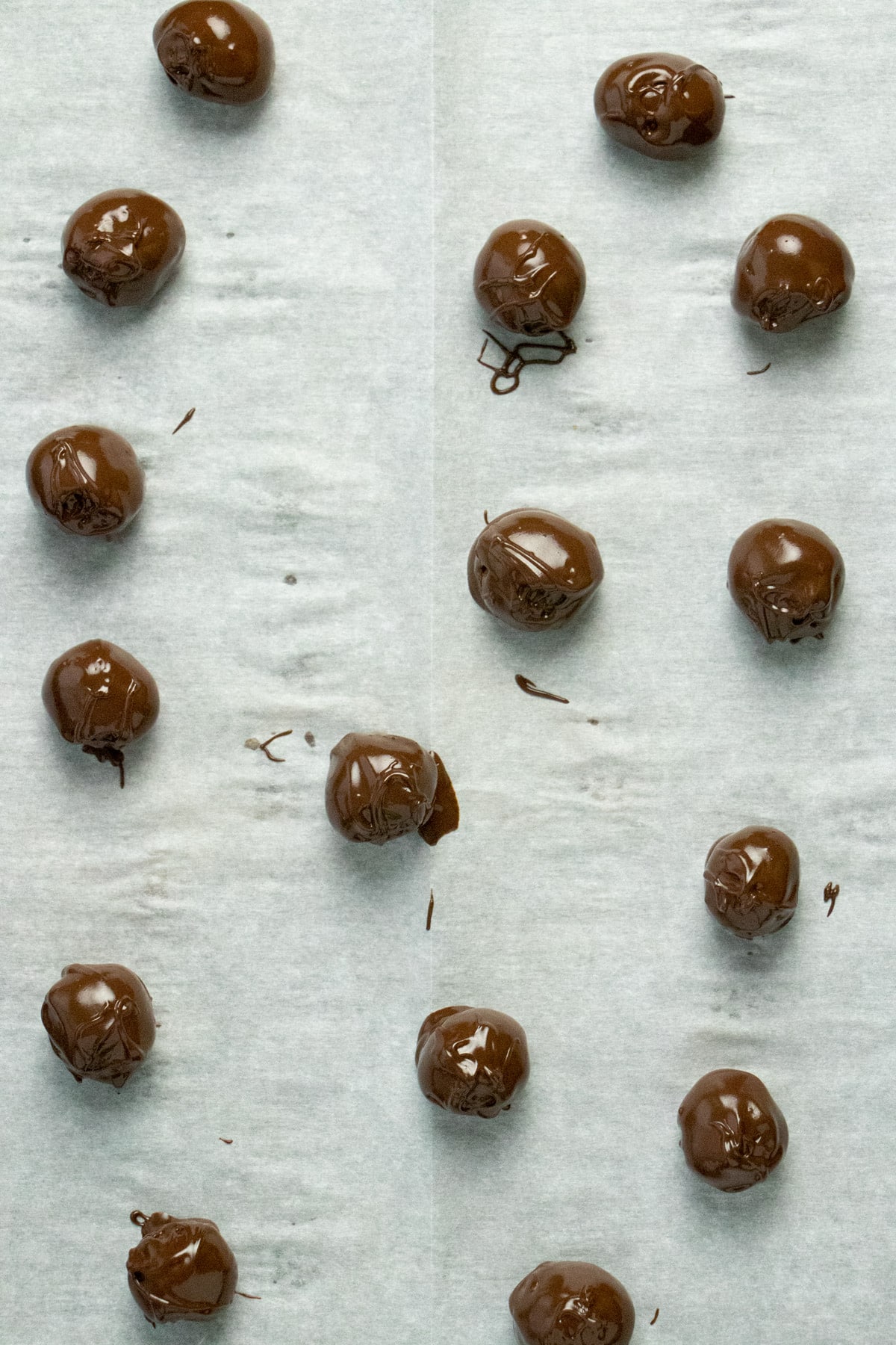 chocolate peanut butter vegan energy balls on a lined baking sheet before chilling the chocolate coating