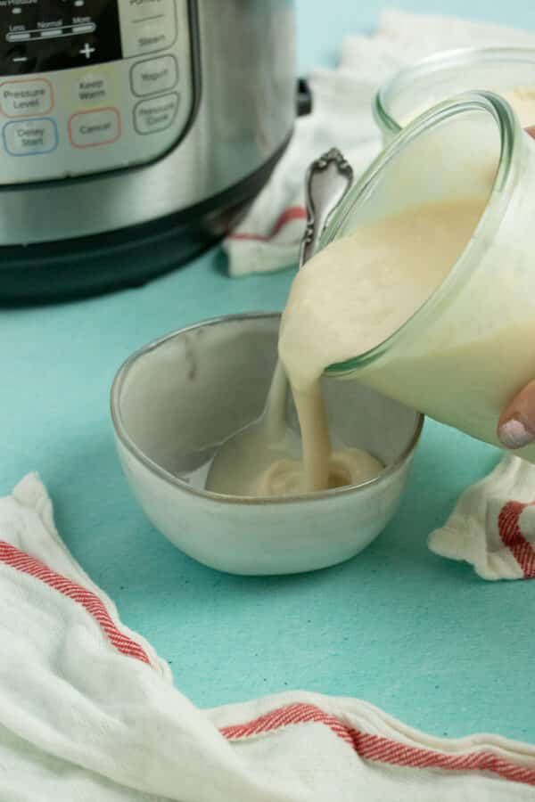 pouring fresh Instant Pot yogurt from the jar into a small bowl