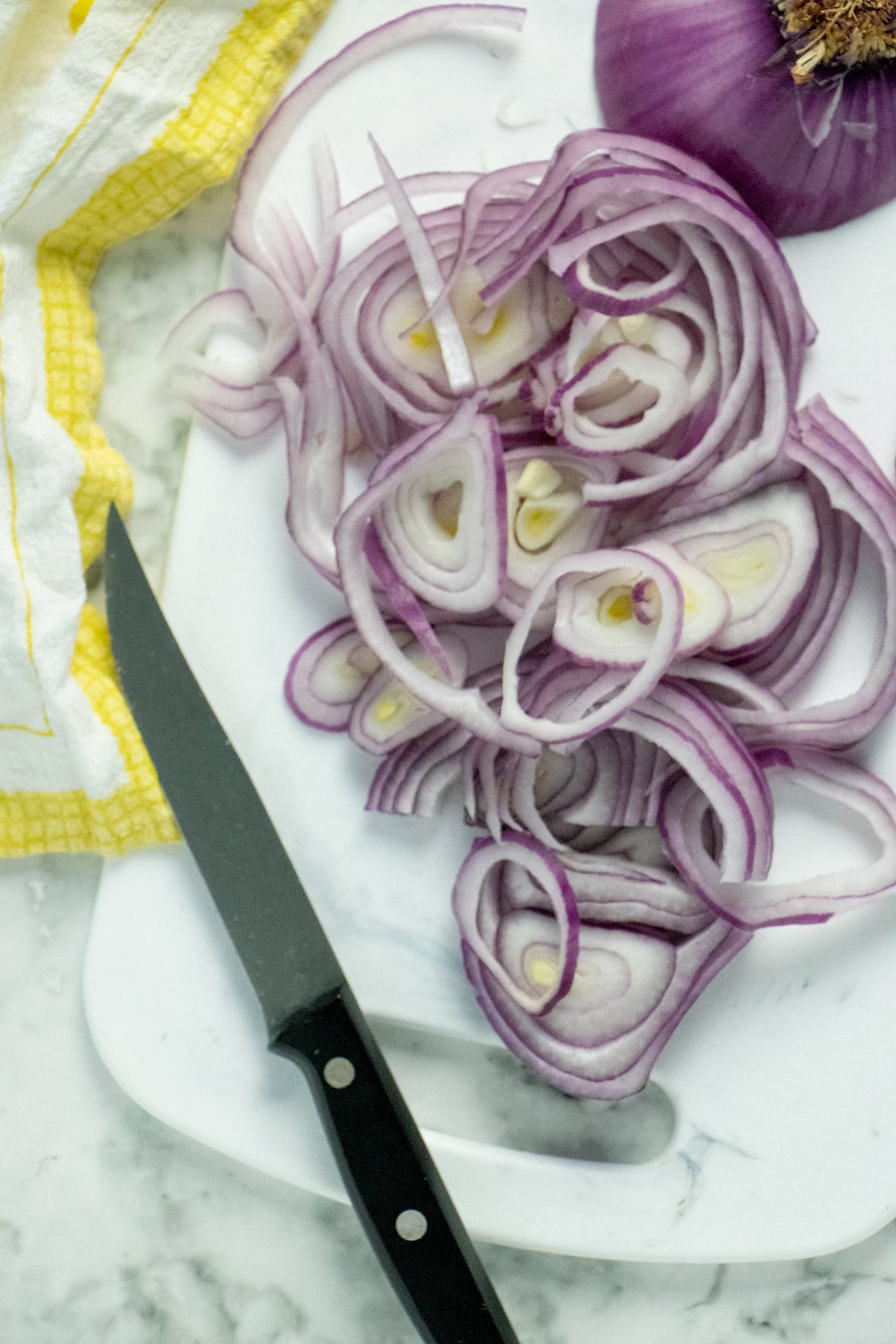 sliced red onions on a cutting board next to a knife