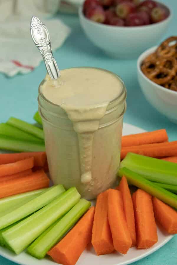 tahini miso dressing on a serving platter with carrots and celery for dipping