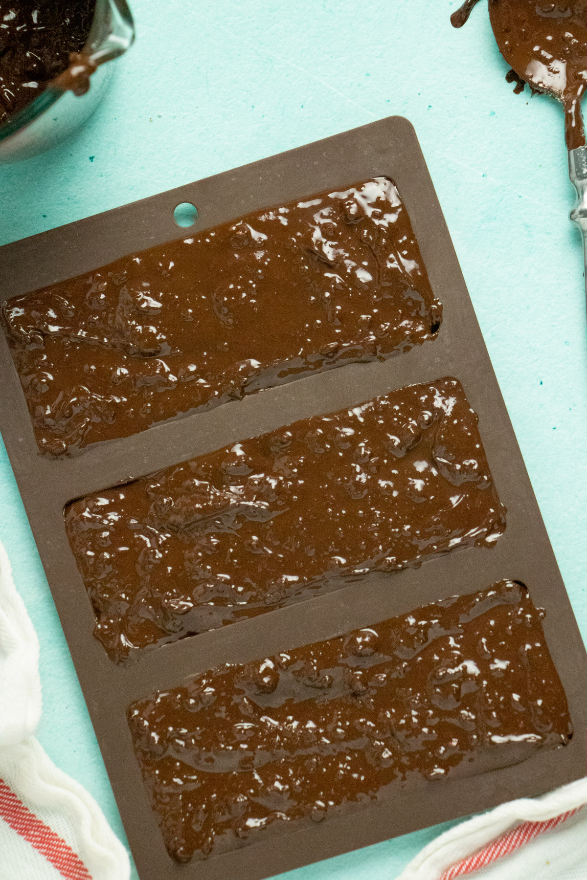 chocolate bar molds filled with vegan chocolate and hazelnut crunch, ready to refrigerate