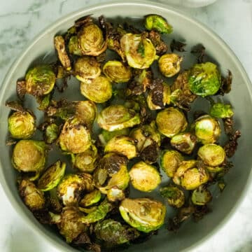 serving dish of air fryer brussels sprouts on a marble tabletop