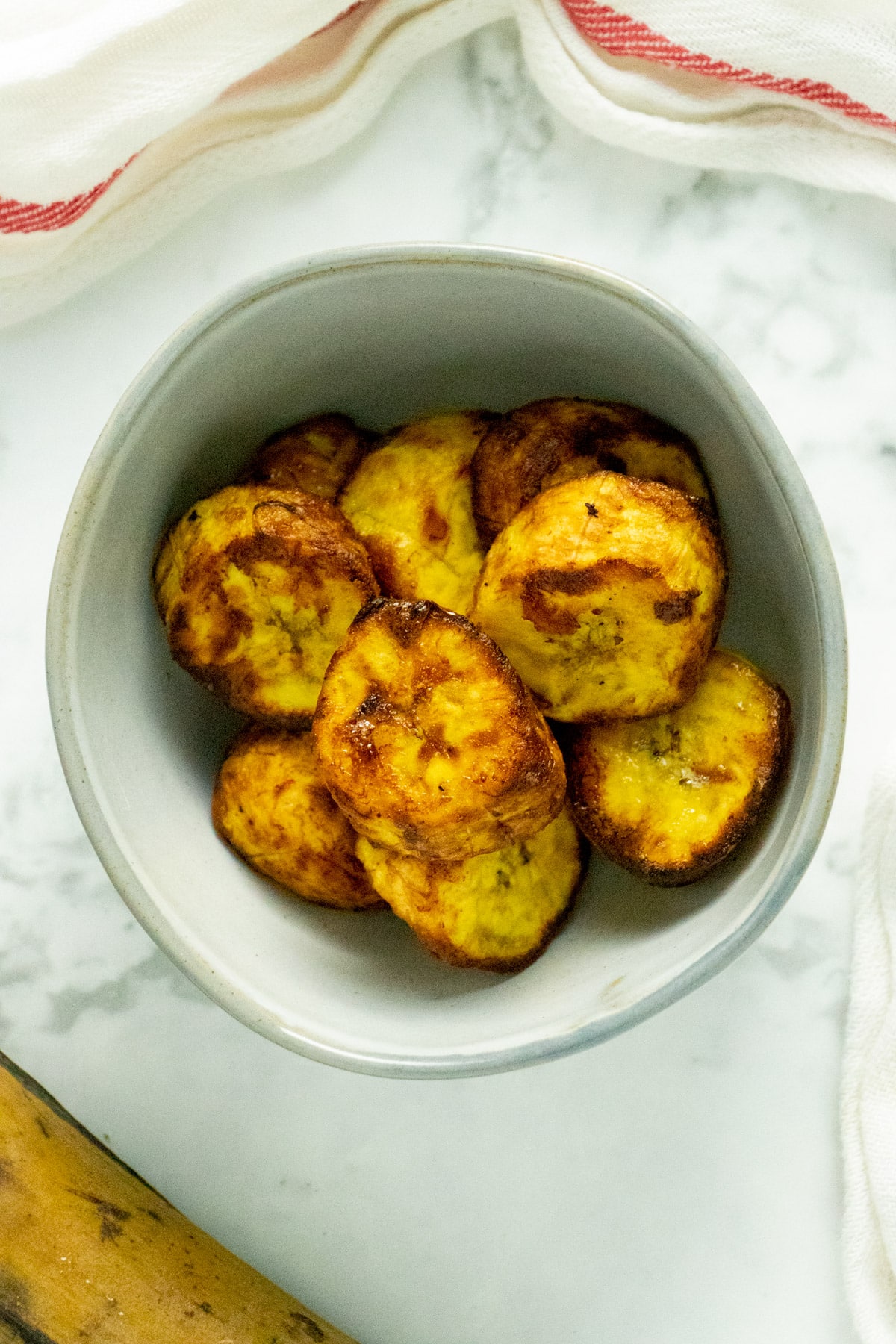 gray bowl of cooked air fryer plantains on a marble tabletop