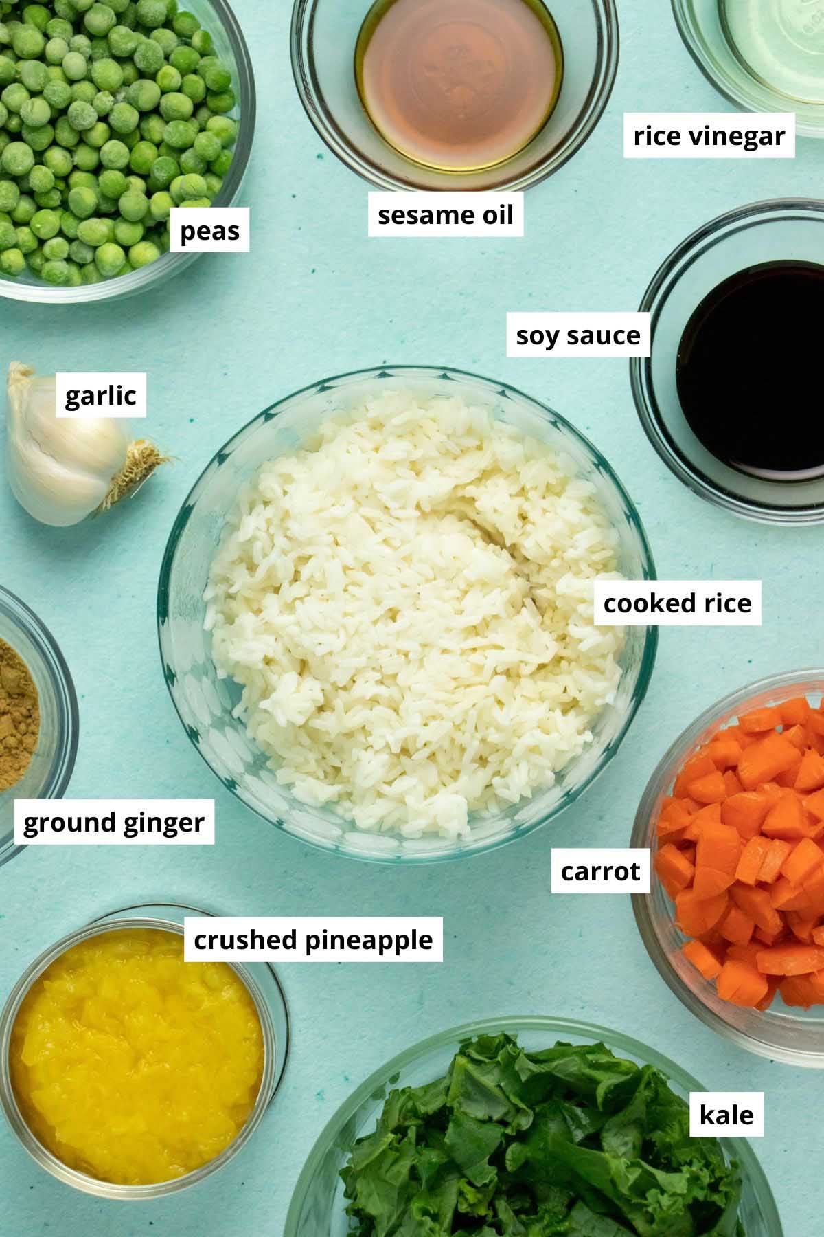 rice, pineapple, veggies, and seasonings in bowls on a blue table