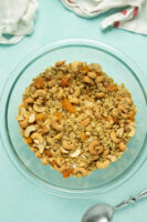 glass mixing bowl of homemade ginger granola with apricots, cashews, and coconut