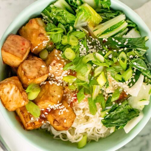 crispy tofu noodle bowl with bok choy, sweet chili sauce, noodles, sesame seeds, and green onion