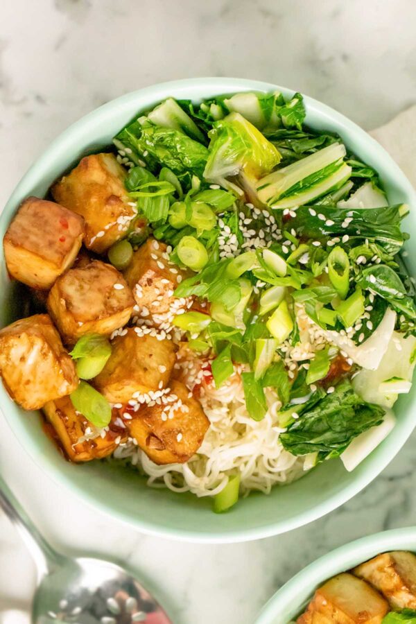 crispy tofu noodle bowl with bok choy, sweet chili sauce, noodles, sesame seeds, and green onion