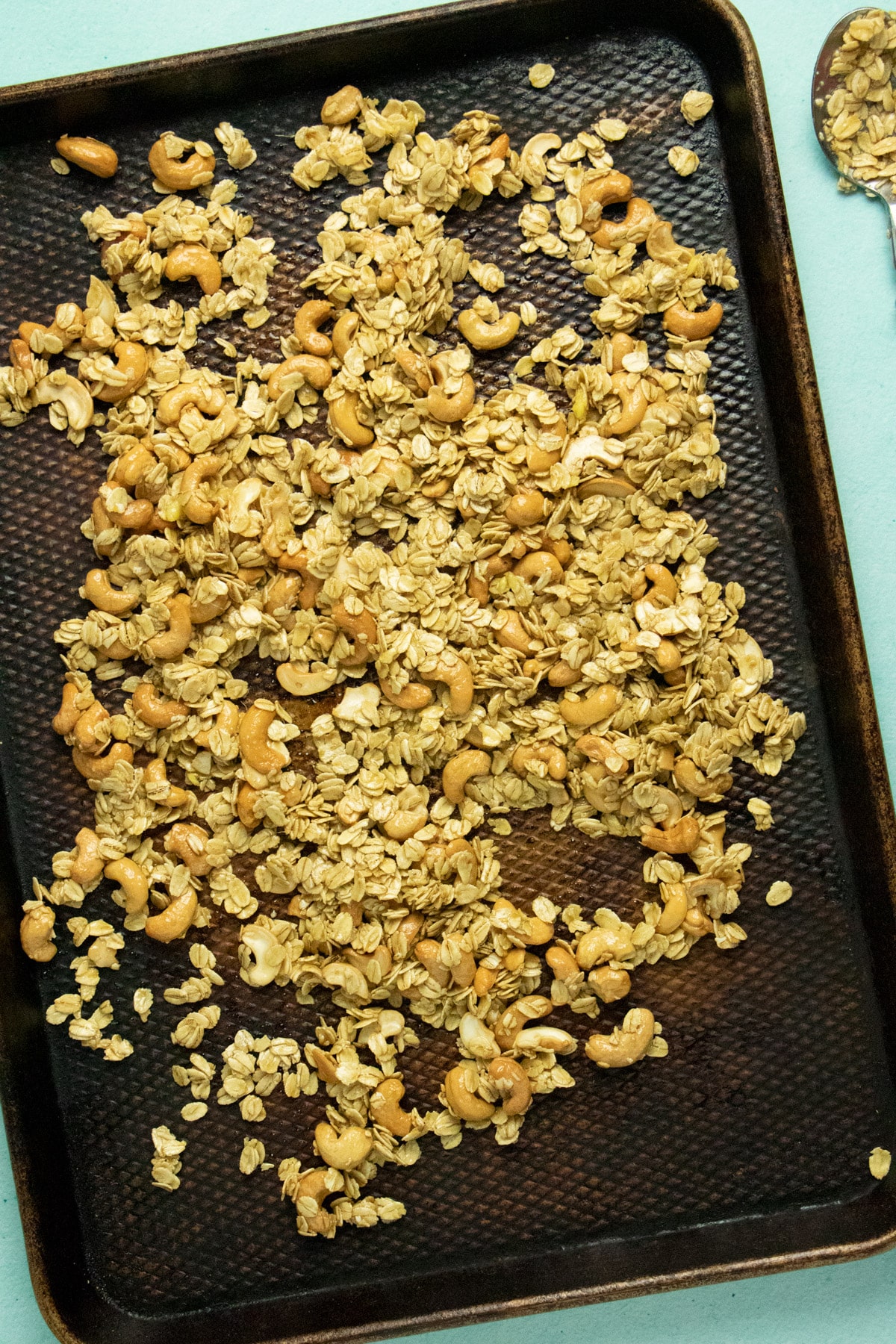 overhead photo of uncooked oats and cashews spread out evenly on a large baking pan