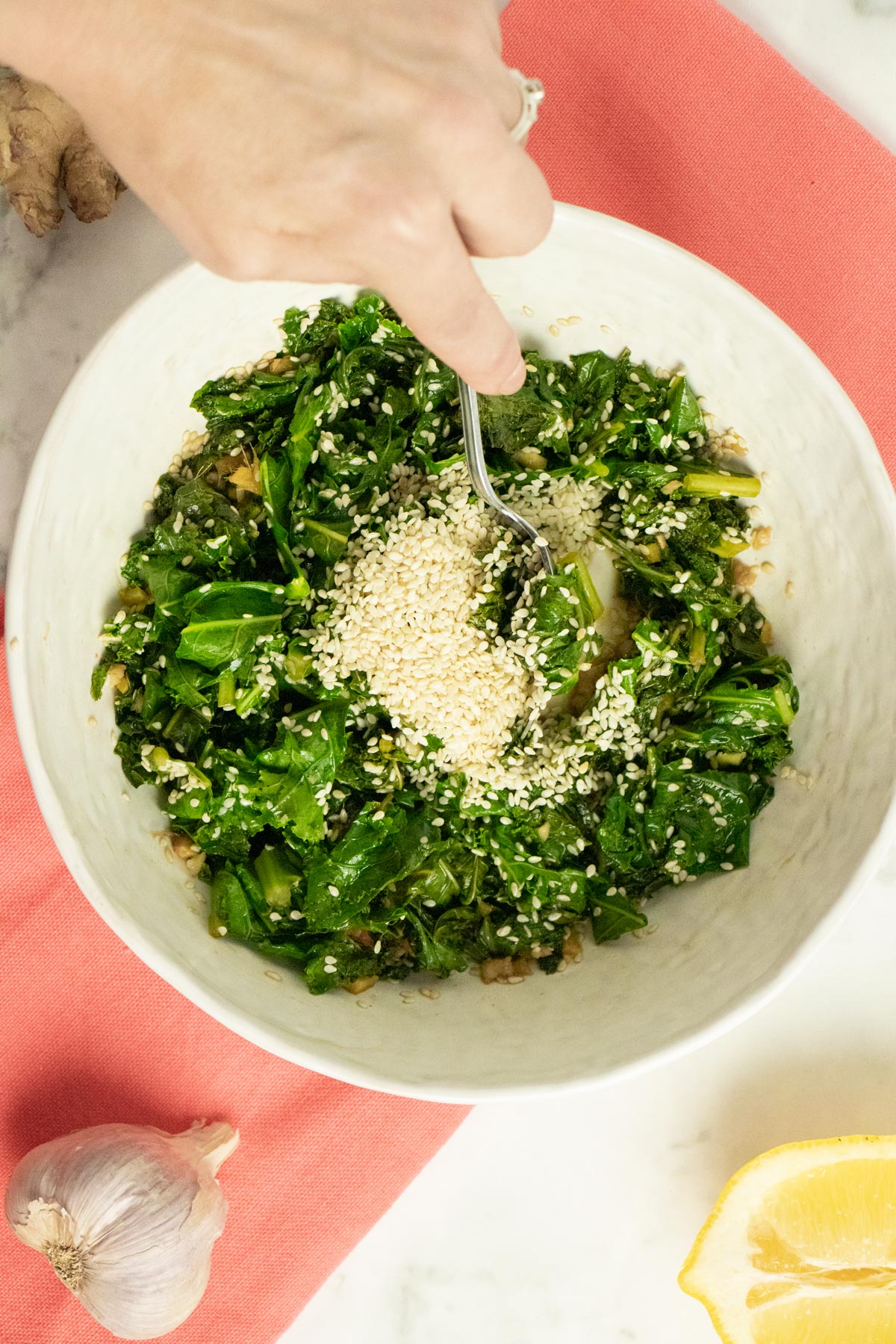 adding sesame seeds to the kale