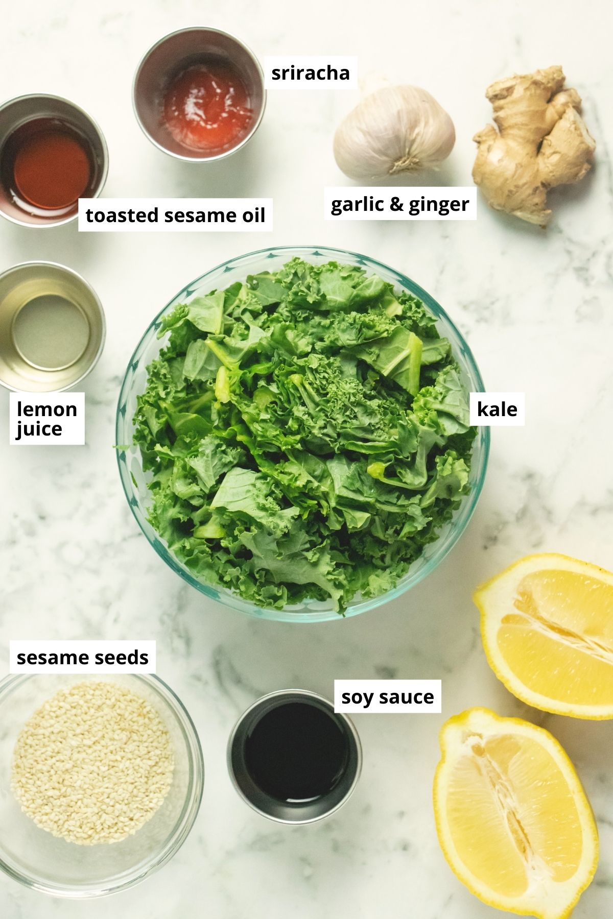 kale, sesame seeds, sesame oil, and seasonings on a white table