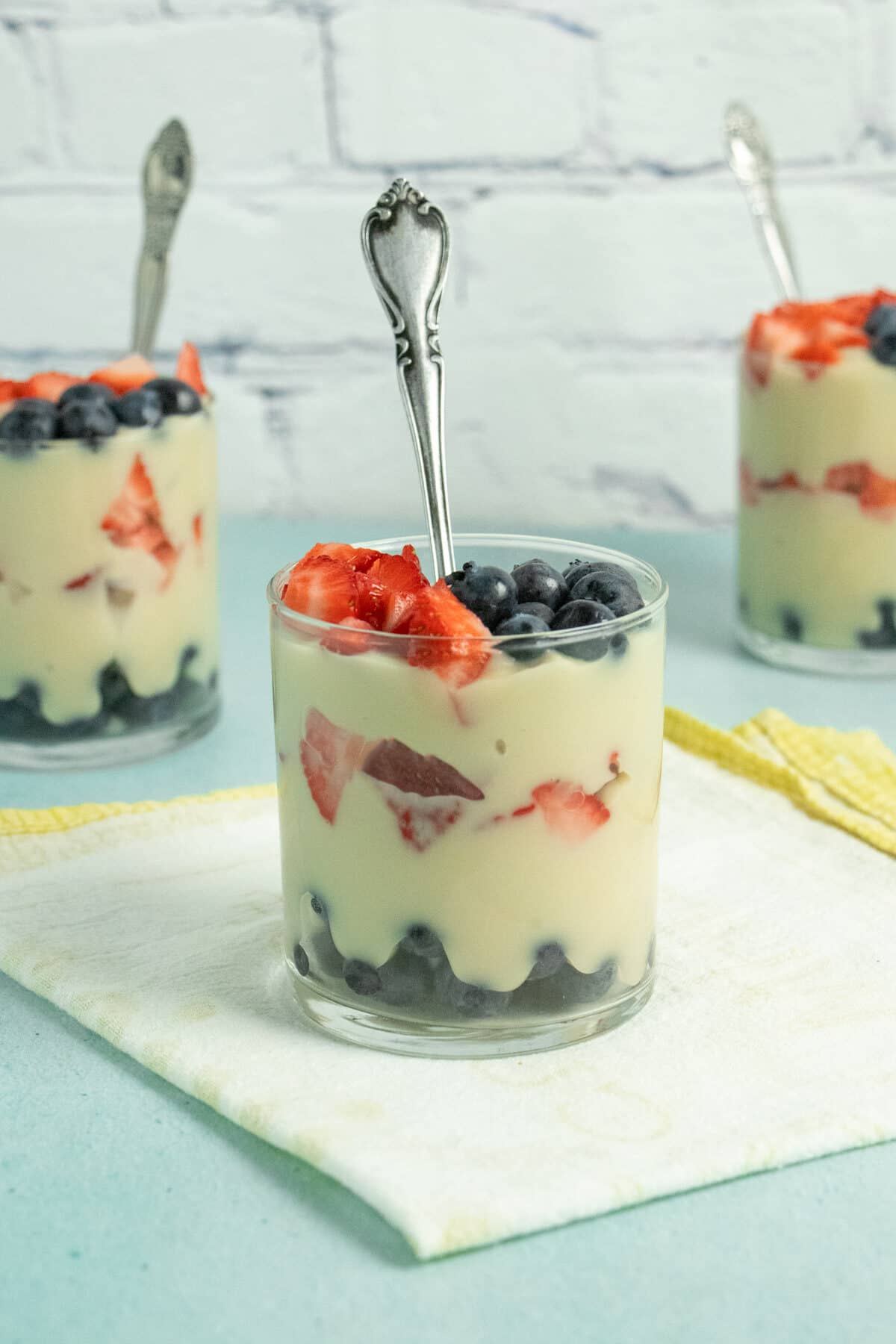 glasses of vegan vanilla pudding layered with strawberries and blueberries
