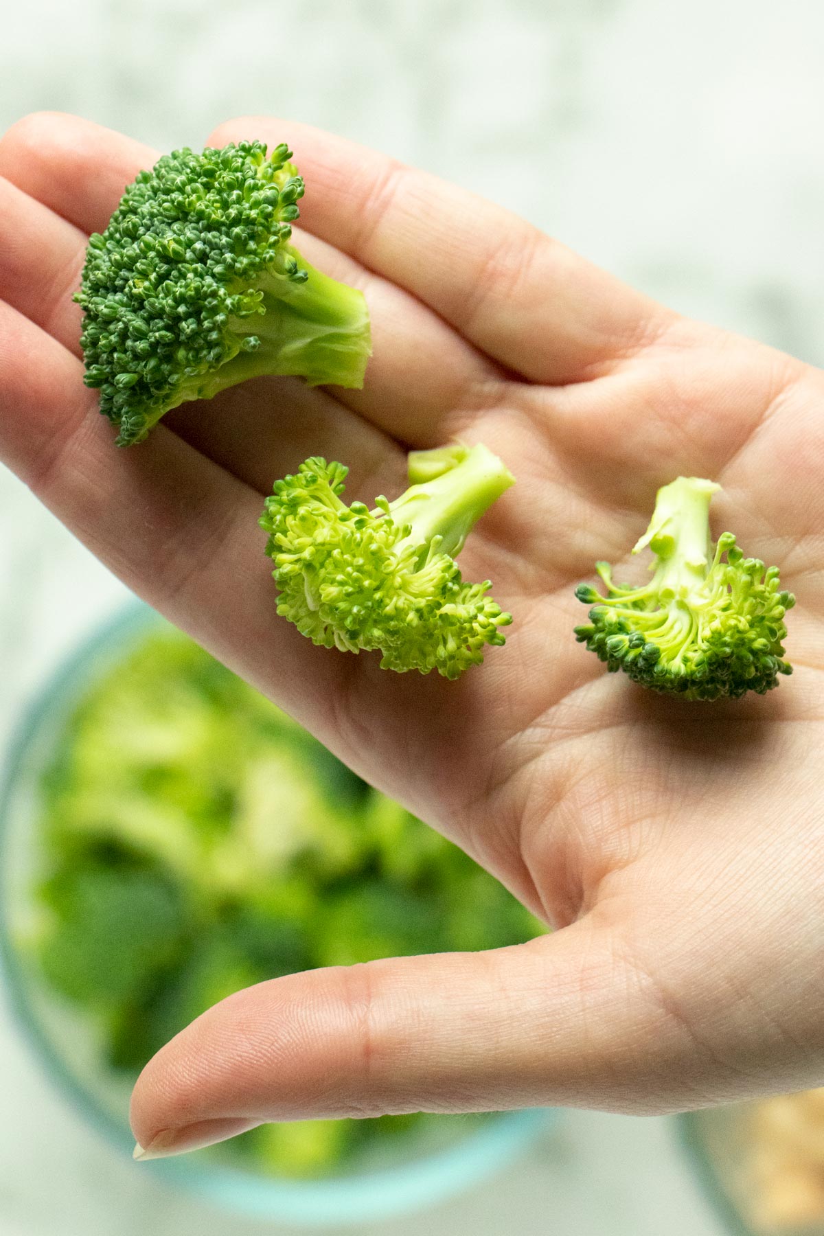 hand holding 3 small broccoli florets