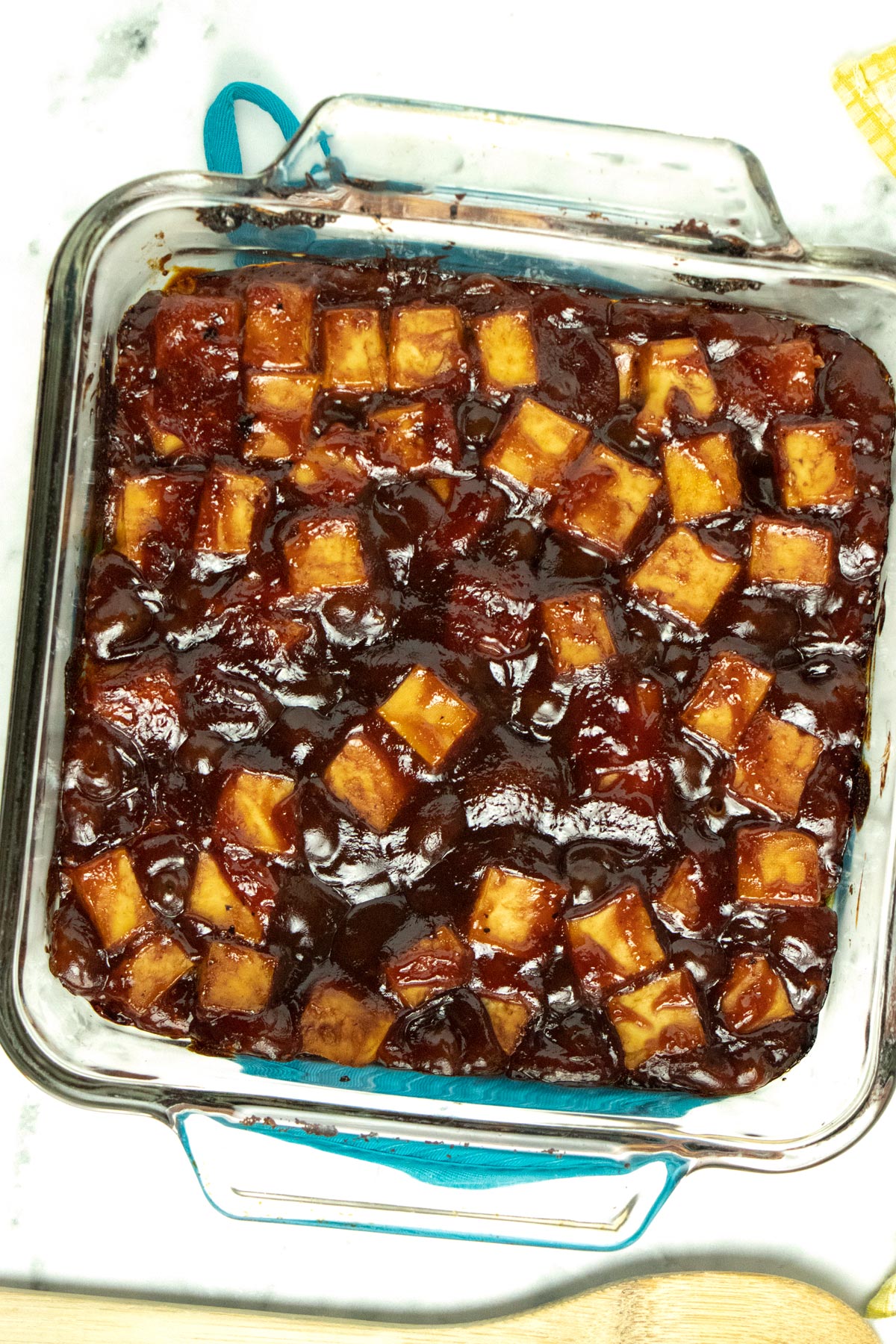 glass baking pan of sticky BBQ tofu on a marble table