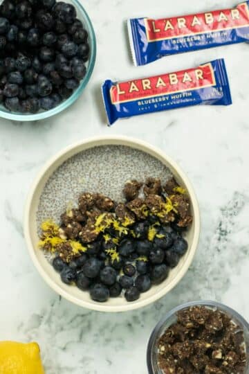 blueberry lemon chia breakfast bowl on a marble table next to Larabars and blueberries