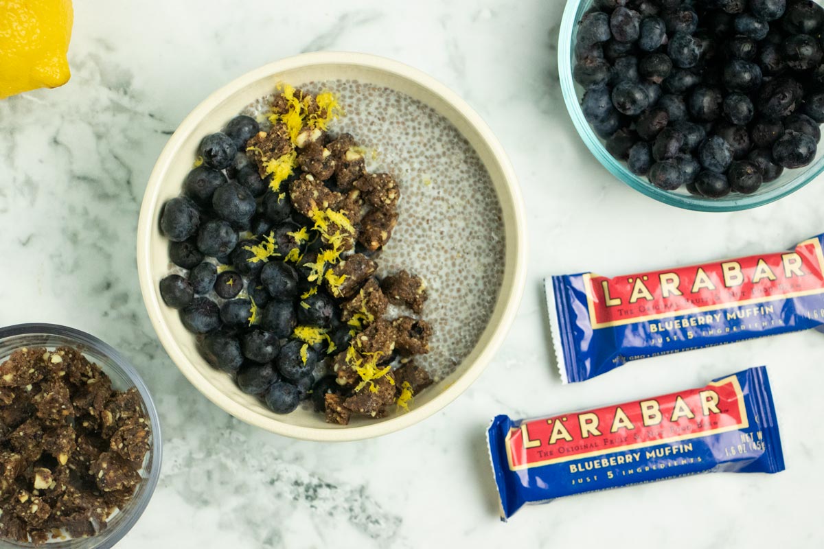 lemon chia breakfast bowl on a marble table next to Larabars and blueberries