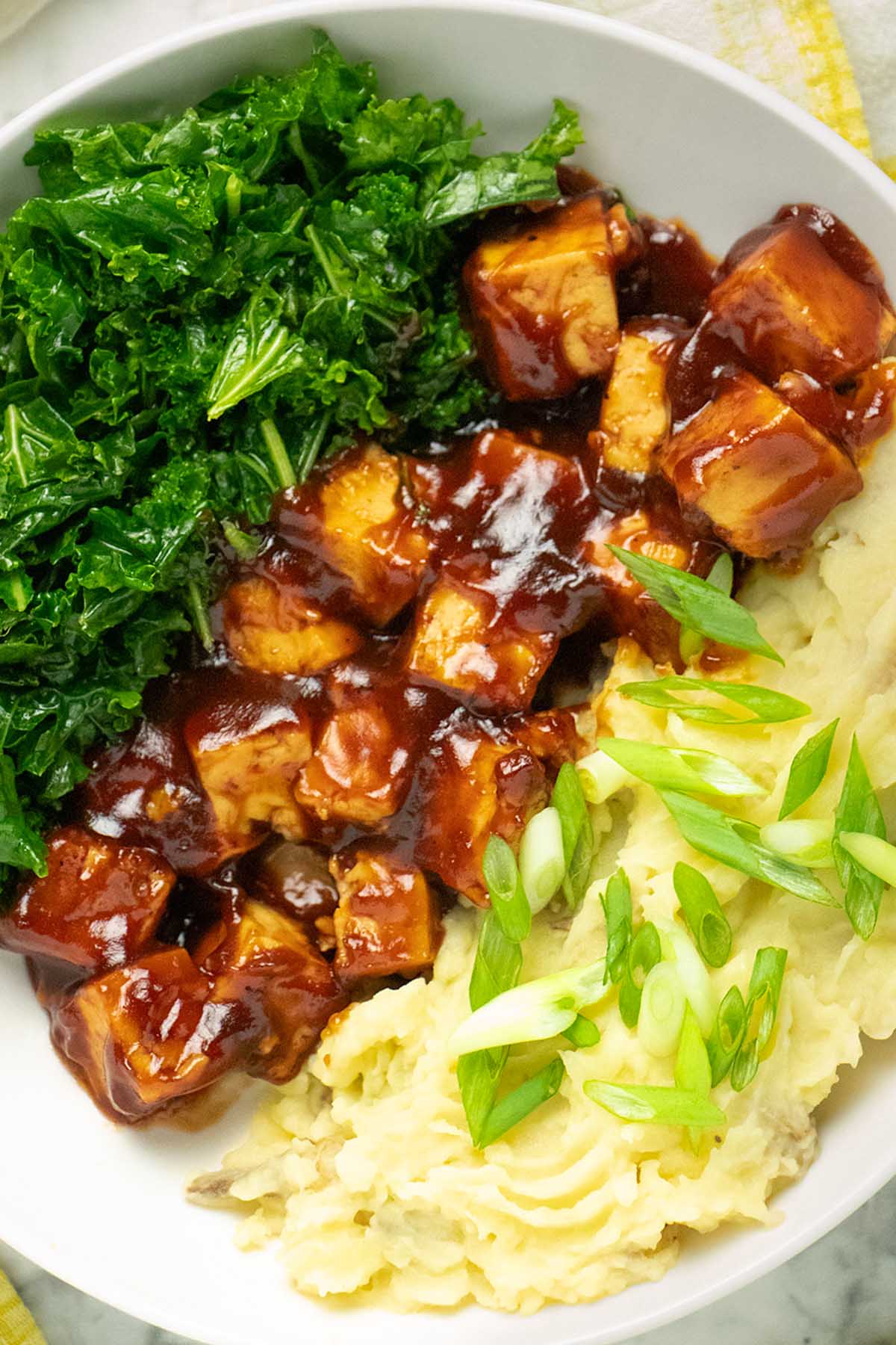close-up of a bowl of baked bbq tofu with kale and mashed potatoes