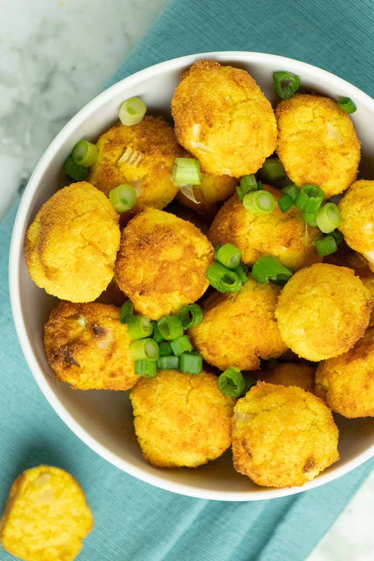 bowl of vegan air fryer hush puppies sprinkled with chopped green onion